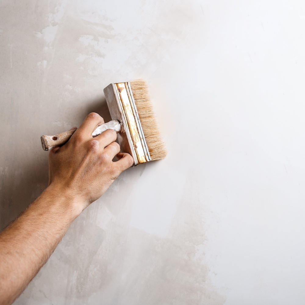 Close up of hand painting wall with brush. Copy space.