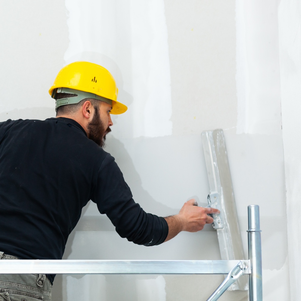 worker plastering gypsum board wall.