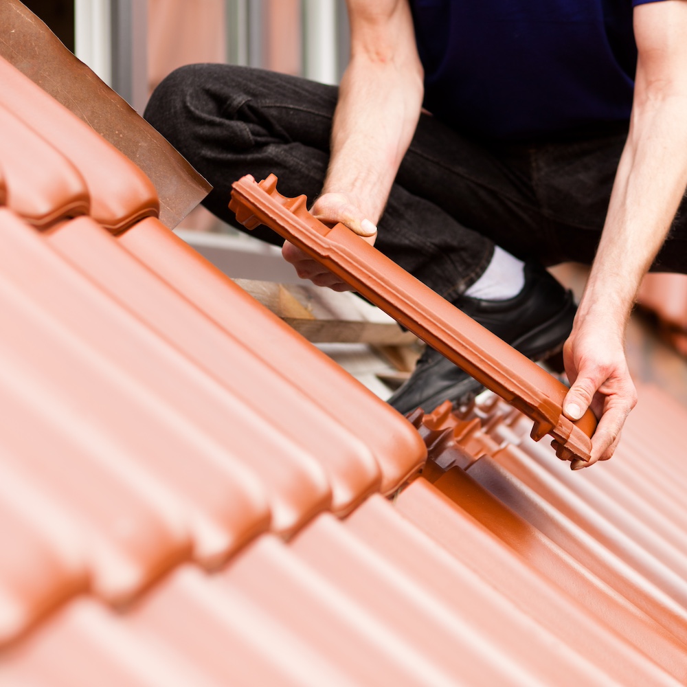 Tiler covering roof with new tile